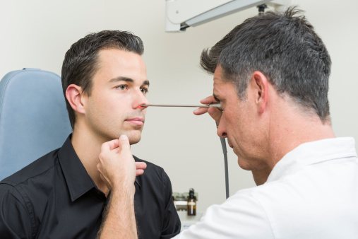 doctor examining nose of patient